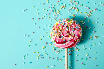 Tuinposter Colorful lollypop candy with red stripes and sprinkles on blue mint background for holidays © Ольга Кан