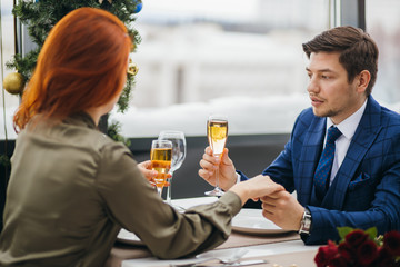 romantic pastime of young beautiful caucasian couple in restaurant. redhaired attractive lady and handsome bearded man in tuxedo on a date. tender relationship between two people in love