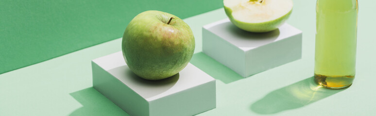 fresh juice near apples and and white cubes on green and turquoise background, panoramic shot