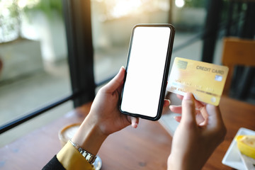 Woman's hands holding smartphone with blank screen and credit card,internet banking, online trading, e commerce concept.