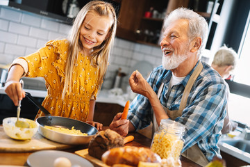 Smiling grandfather helping children to cook in the kitchen