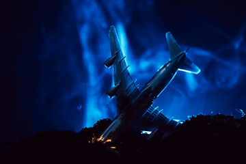 Battle scene with crash of toy plane with blue smoke on black background