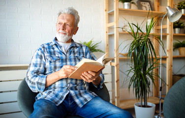Senior man at home reading book and enjoying retirement, penison