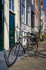 Fototapeta na wymiar A rusty bicycle parked outside on a cobblestone sidewalk in an iconic neighborhood of Amsterdam