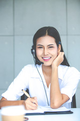 Attractive business woman Asian in suits and headsets are smiling while working with computer at office. Customer service assistant working in office