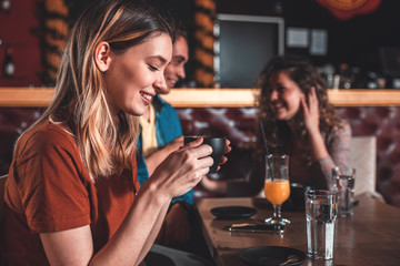 Portrait of young woman enjoying drinking coffee in cafe with her friends.