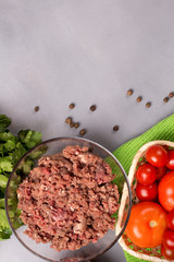 Minced meat with tomatoes, eggs, parsley and pepper on a gray background. Forcemeat. Top view.