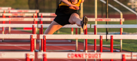 One athlete running in the hurdles
