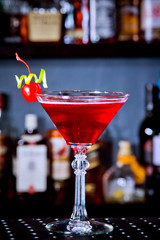 Red drink cocktail with cherry in martini glass, cherry and lime peel