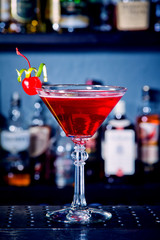 Red drink cocktail with cherry in martini glass, cherry and lime peel