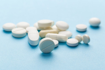 scattered white pills on a blue table. Layout for special offers such as advertising or other ideas. The concept of medicine, pharmacy and healthcare. Space for copy. flat lay for text or logo.