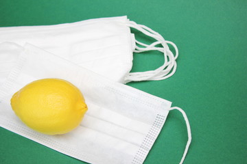 A yellow lemon is located on a pile of medical masks. Medicine and healthcare.