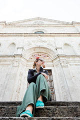 Fototapeta na wymiar Young female traveler sitting on church steps in old town in Tuscany, Italy
