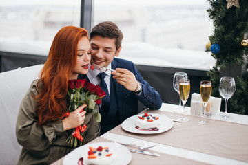 beautiful caucasian couple celebrating saint valentines day in restaurant, sit at table, enjoy having dinner together, man in tuxedo and woman in dress. celebration, relationship, love concept