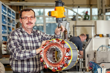 Fototapeta Skilled industrial worker assembling a large electric motor obraz