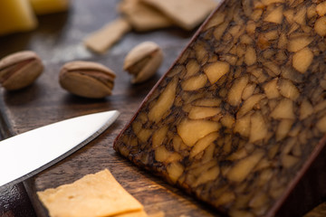 close up view of cheese platter with crackers and pistachios near knife