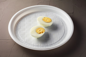 cut egg in a disposable plate on a concrete background