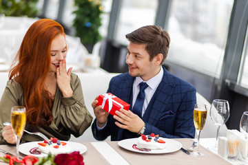 surprised redhaired lady in dress happy to be with her gallant boyfriend. young and beautiful woman is happy, in love. man made romantic date to lovely, cute female. celebration, love, emotions