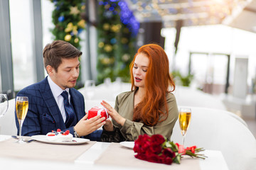 beautiful attractive redhaired lady and handsome guy in tuxedo sit together in restaurant, celebrating st valentines day. love, emotions concept