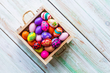 Easter holiday concept,Colorful Easter eggs in basket on white pastel color rustic wood background with space.