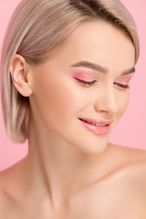 Fototapeta premium beautiful smiling girl with pink makeup, isolated on pink