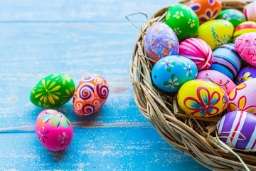 Easter holiday concept,Colorful Easter eggs in basket on blue pastel color rustic wood background with space.