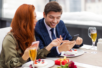 beautiful caucasian couple spend time together in restaurant, attractive lady and handsome man sit at table, enjoy being together, eating pavlova cake dessert made in representative rich restaurant