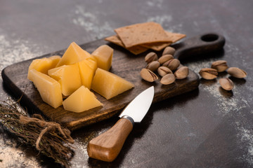 cheese platter with Grana Padano, crackers and pistachios near knife