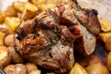 A piece of juicy meat baked in an oven in a glass bowl with a crust and potatoes