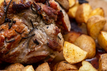 A piece of juicy meat baked in an oven in a glass bowl with a crust and potatoes