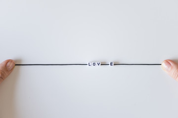 Love word made from letters printing blocks on a black rope. White background