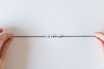 Love word made from letters printing blocks on a black rope. White background