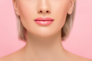 cropped view of young woman with perfect skin and pink lips, isolated on pink