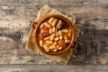 Typical Spanish fabada asturiana in crockpot on wooden table. Top view