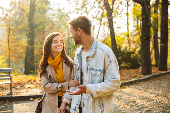 Image of attractive young caucasian couple walking through autumn park