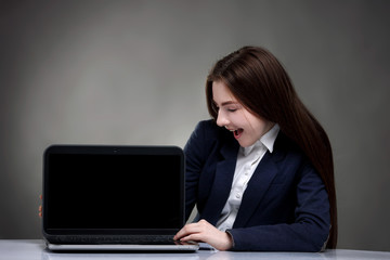 Pretty teen girl sitting at table with laptop.Surfing the NET