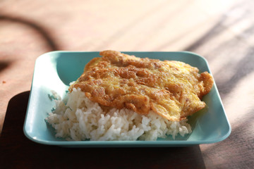 usmine rice topping with omelette with pork or minced pork in omelette serve on white plate and on white wooden table