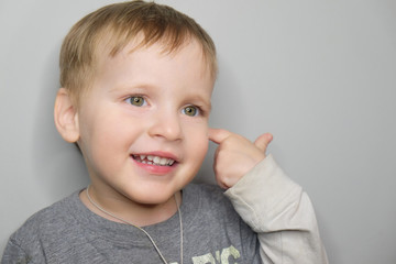 Studio close-up portrait of beautiful smiling baby boy isolated on grey background