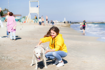 Lovely young woman walking the dog on the beach