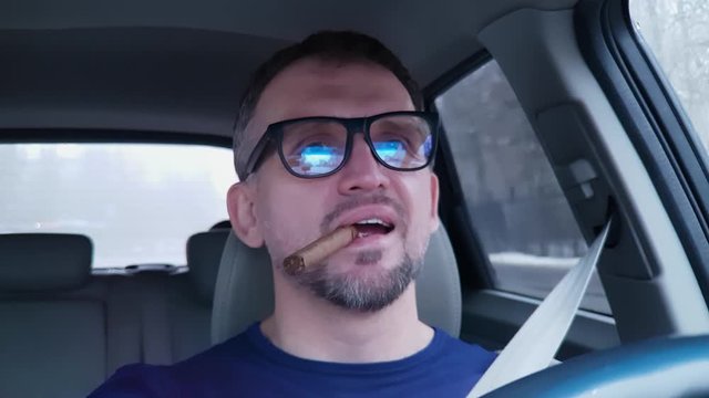 Caucasian man driving passenger car with cigar smiles and nods to music
