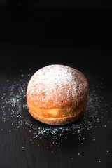 Food concept single Beignet French yeast doughnut deep-fried choux pastry on black slate board background