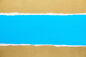 Blue torn piece of cardboard on golden brown paper texture background. Copy space for text message.