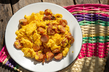 Scrambled eggs with sausage breakfast on wooden background