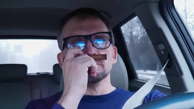 White bearded man behind steering wheel of passenger car is happy to sniff an unlit cigar