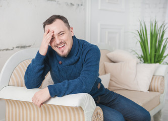 Handsome man laugh sitting on couch at home