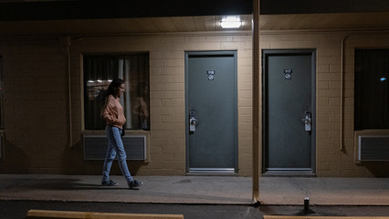 Woman walking along a motel alley like in Drive - obrazy, fototapety, plakaty