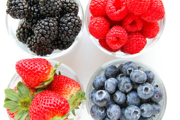 Assortment of fresh berries on a white background. Raspberries, blueberries, blackberries, strawberries in small glasses. Healthy eating. Vegan food. 
