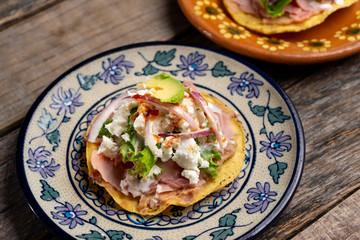 Mexican ham toast also called tostadas with beans and cheese on wooden background