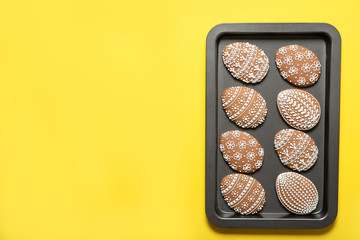 Easter cookies on a baking tray on a yellow background. Top view. Easter eggs.
