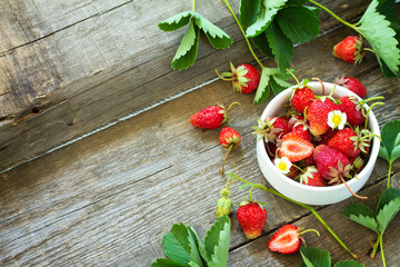 Fresh strawberries in a bowl on a wooden rustic table. Copy space.